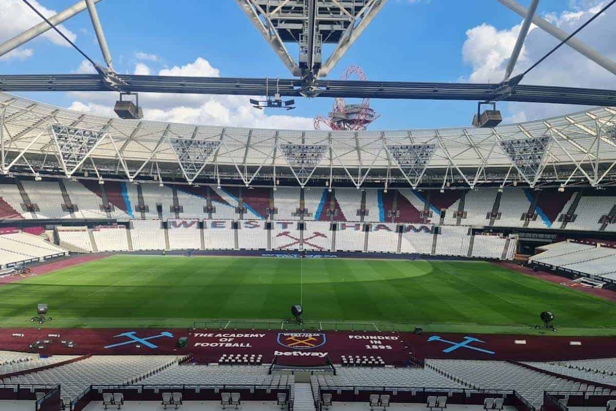 a stadium with a green field and white seats