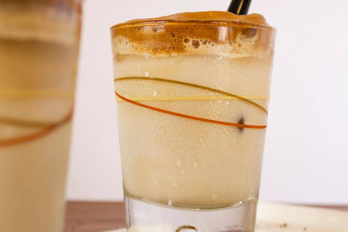 whipped coffee in a small glass with a black straw.