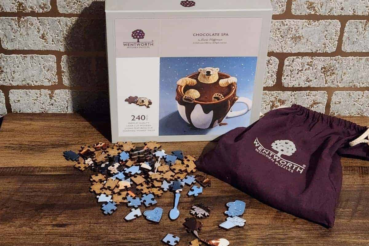 This delightful 240-piece jigsaw puzzle with a chocolate spa theme is the perfect Christmas gift for a family. It features pieces partially assembled on a wooden table and comes with a stylish Wentworth-branded cloth bag, ensuring both fun and elegance.