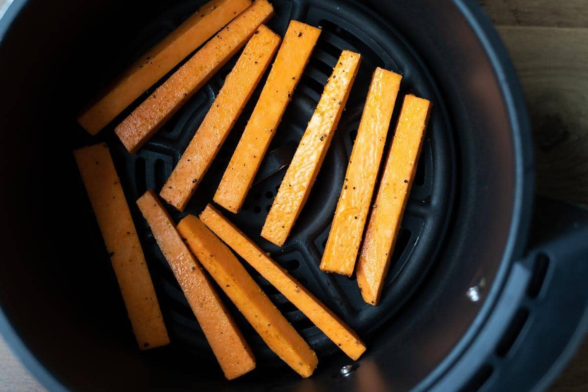 Raw sweet potato fries in an air fryer.
