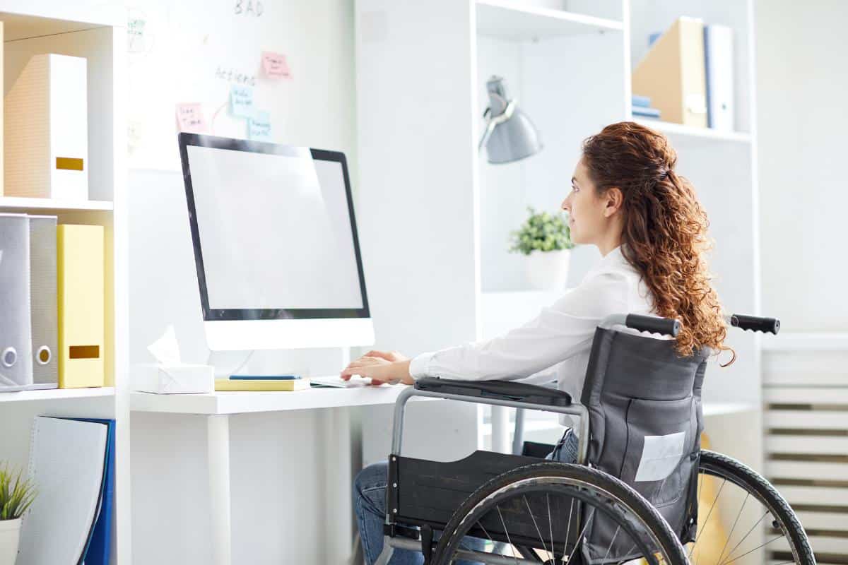 Lady in a wheelchair at a standing desk adjusted to the correct height.