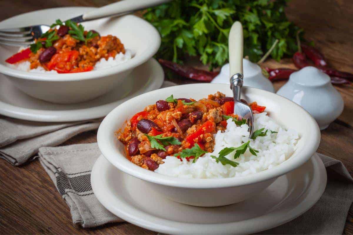 two white bowls with chilli con carne and rice in
