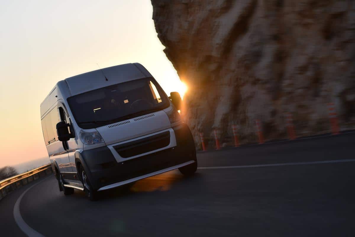 van driving along a road next to cliffs