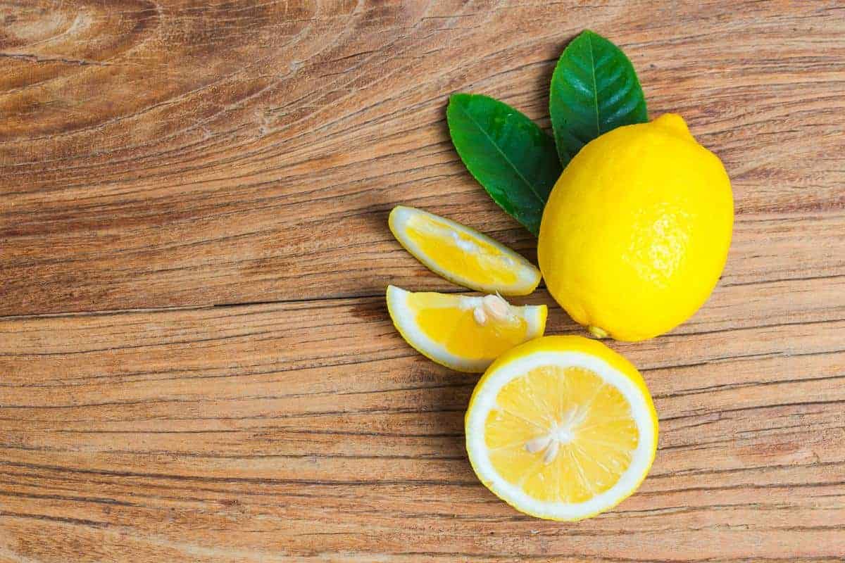 Whole lemon and cut lemon on wooden surface