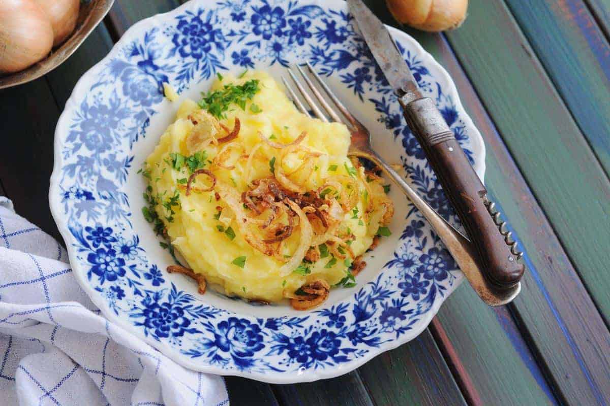 Bowl of Slimming World mashed potatoes topped with fried onions.