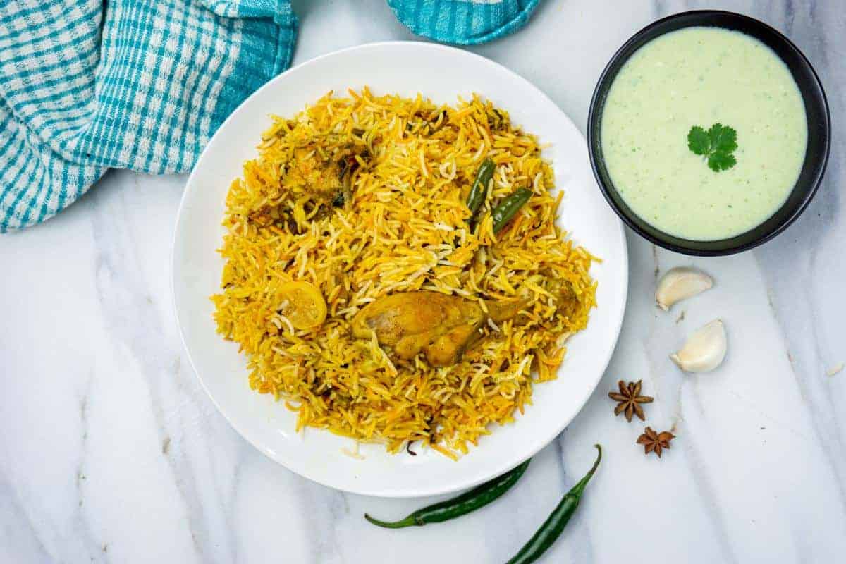 plate of chicken biryani with a bowl of raita