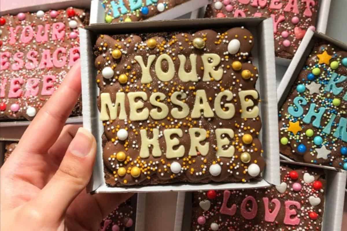 A chocolate square brownie with \"your message here on the top\".