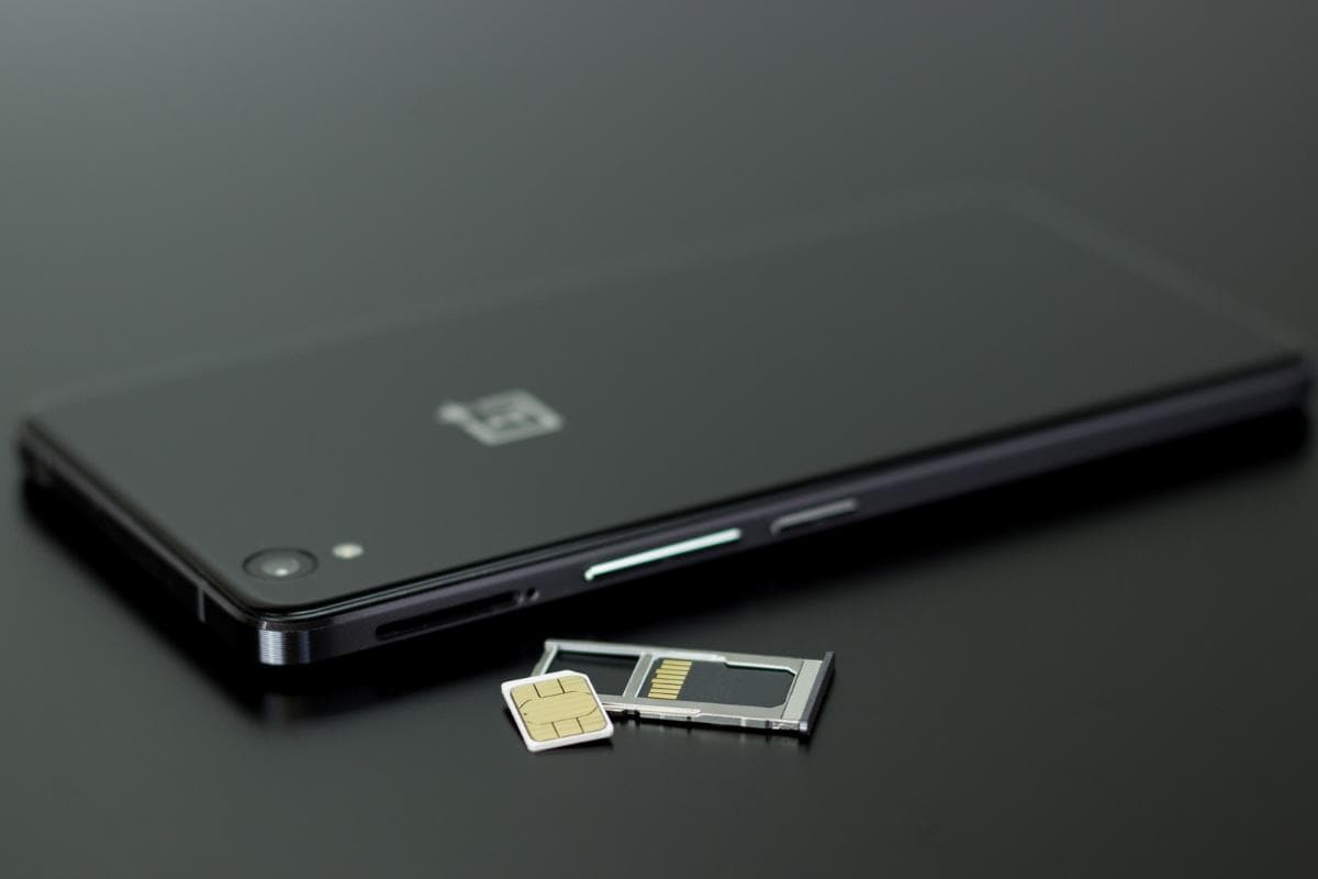 A phone with a sim card tray removed and sim care and memory card out.