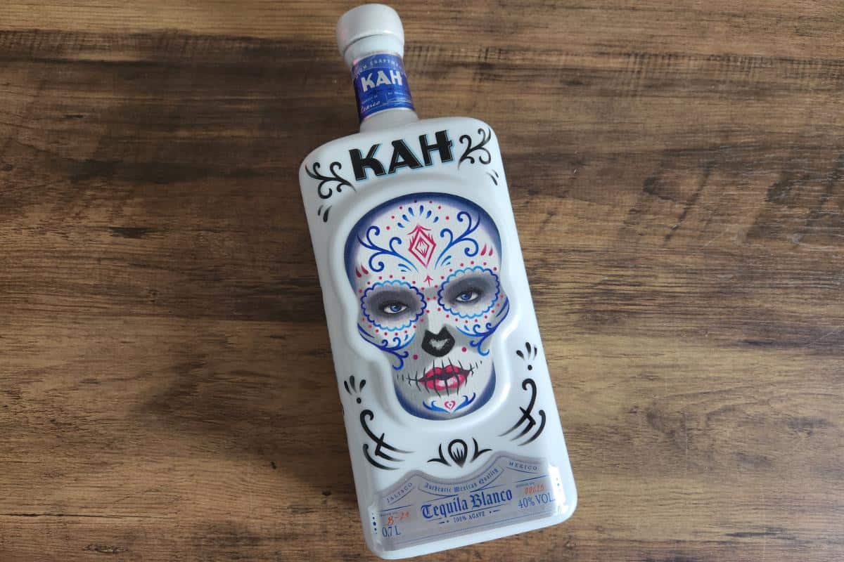 Bottle of KAH tequila which is a white bottle with a decorated skull in a day of the dead type theme.