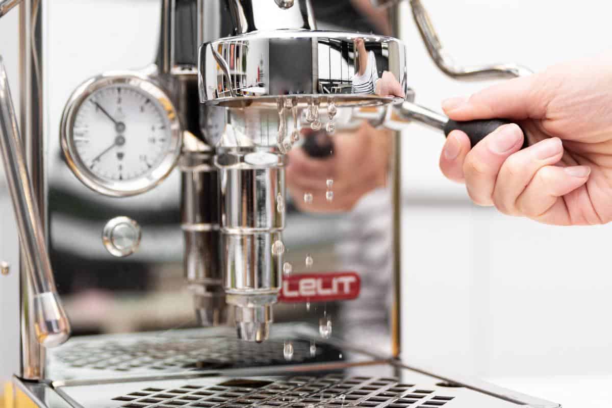 A shiny silver coloured coffee machine being cleaned.