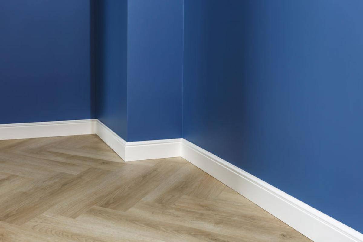 wooden floor with white skirting boards and a blue wall.