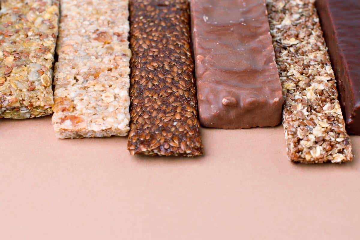 A selection of different protein bars some topped with chocolate other just seeds.