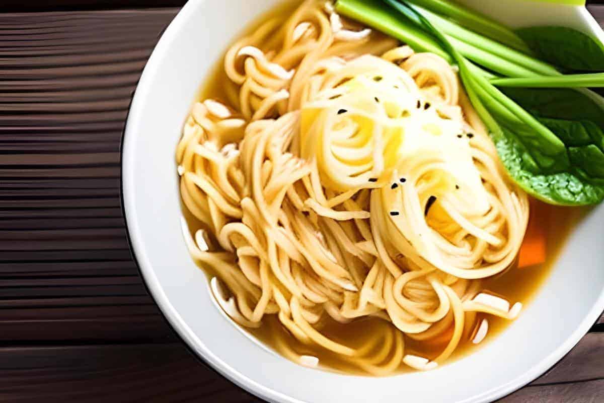 bowl of plain ramen noodles with a brown broth and spring onions.
