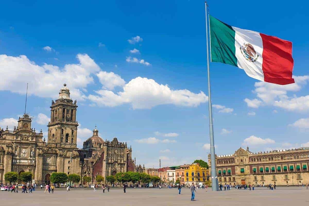 Square in the centre of mexico with a flag flying on a sunny day