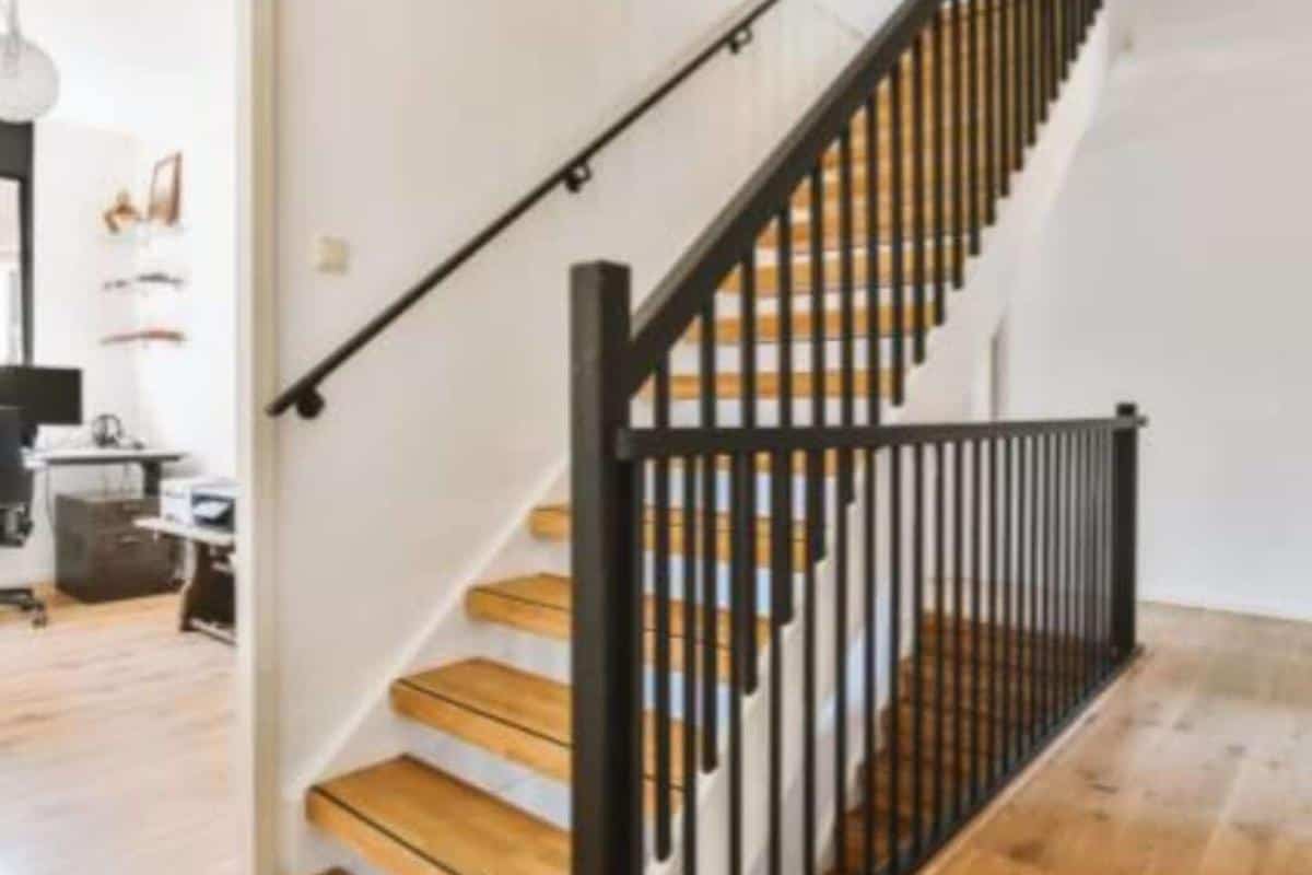 A painted wooden staircase with bare wooden stairs and a dark painted wooden banister.