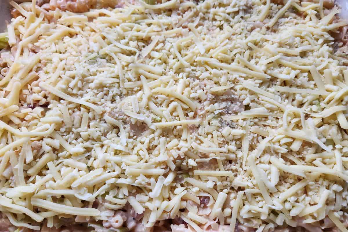 Macaroni cheese topped with grated cheese before it is put in the oven.