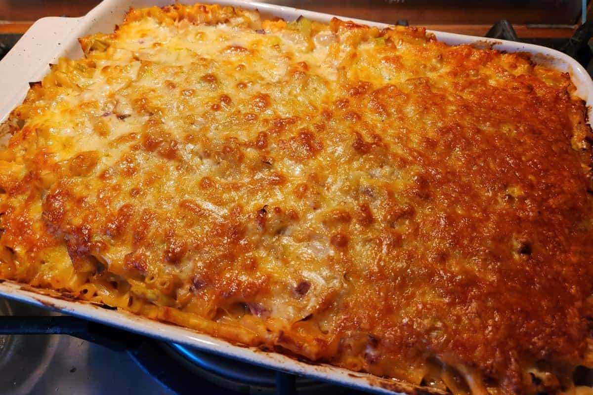 Oven dish full of leek macaroni cheese with a golden cheese top.