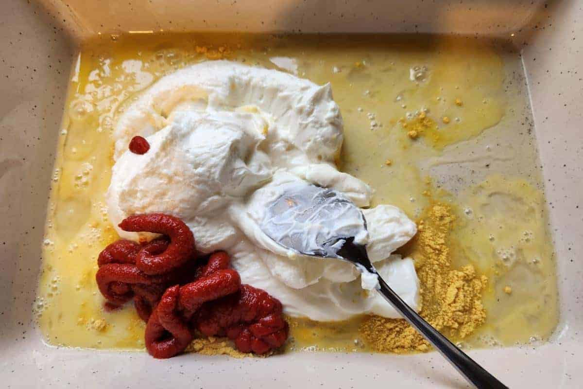 Oven dish containing quark, tomato puree, eggs and mustard powder.