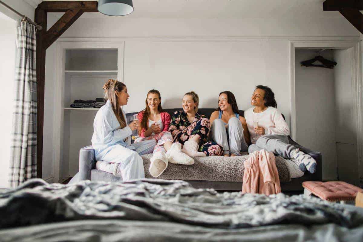 five young women all laughing and chatting wearing different types of nightwear and pyjamas.