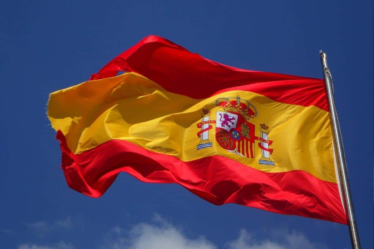Spanish flag blowing in the wind with a blue sky behind.