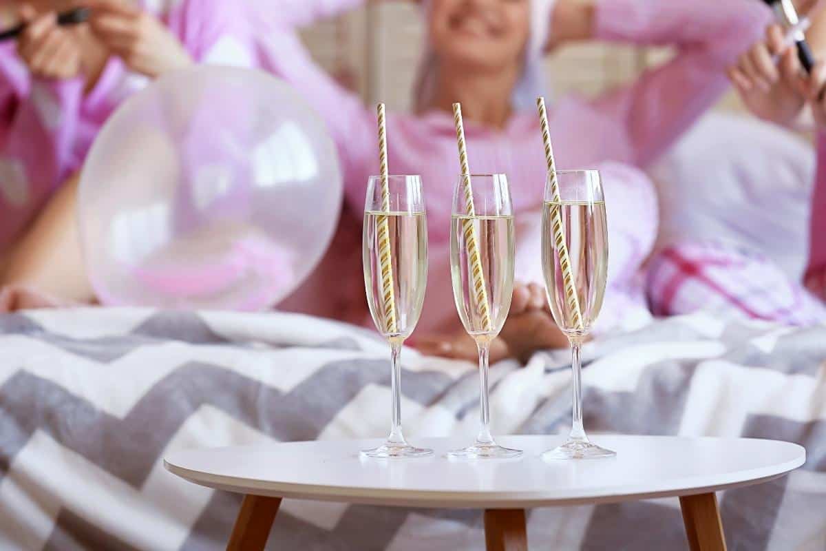 champagne at hen party with women sitting in pink in the background enjoying the hen do.