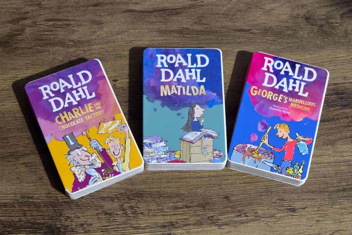 Three Roald Dahl book covers rest on a wooden surface: "Charlie and the Chocolate Factory," "Matilda," and "George's Marvellous Medicine." These timeless tales make charming gifts for babies as they grow into young readers, sparking imaginations from an early age.