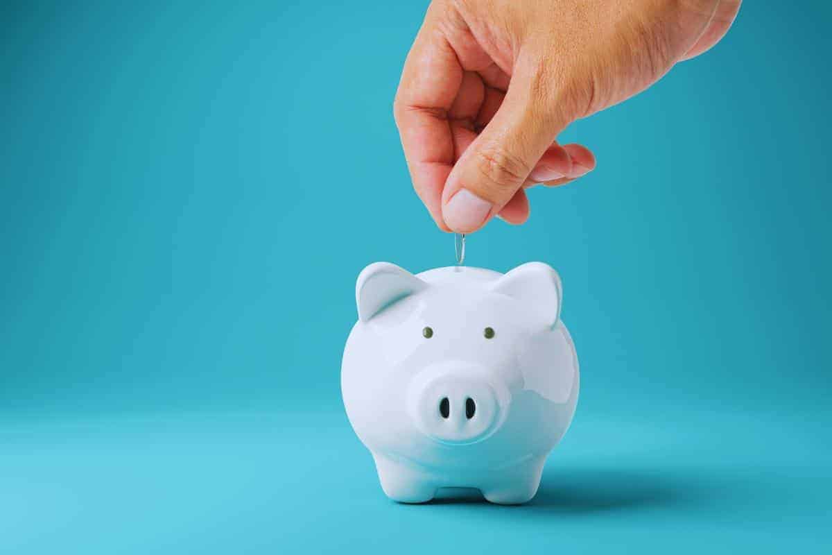 Hand placing a coin into a white piggy bank against a blue background, symbolizing the start of financial security. Claim your free Child Trust Fund today and see how the government set up savings can grow over time.