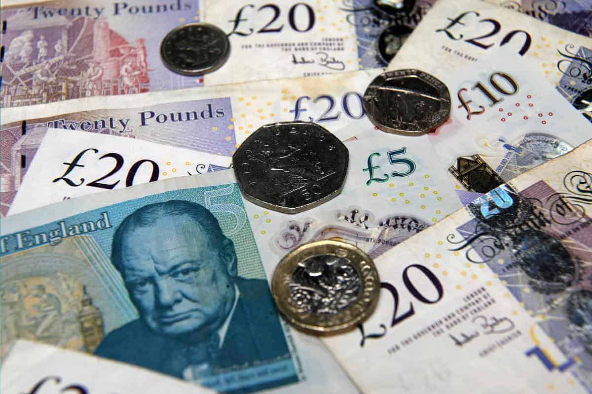 British currency, including £20 and £10 banknotes, along with 50p and £1 coins, are spread out randomly—a reminder of how the government ensures you claim every benefit available, like a Free Child Trust Fund.