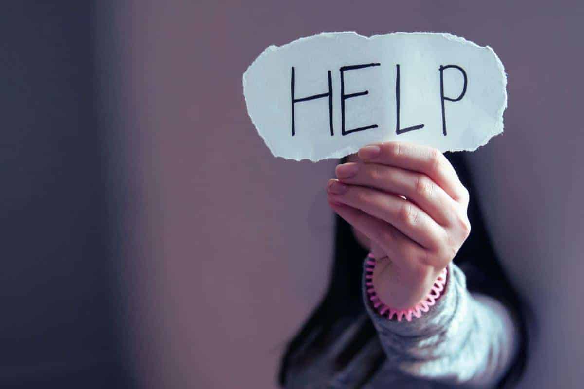 Lady with dark long hair holding a torn piece of paper with the world help up to the screen as I ask for help with my weight.