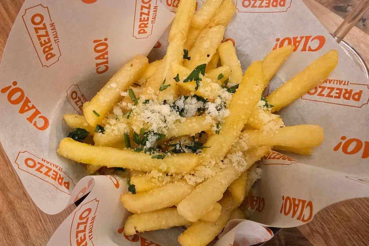 A serving of golden French fries topped with grated cheese and herbs, placed in a paper-lined basket branded with “PREZZO ITALIAN” and “CIAO!”—a delicious bite perfect for your next Nottingham Prezzo Italian review.
