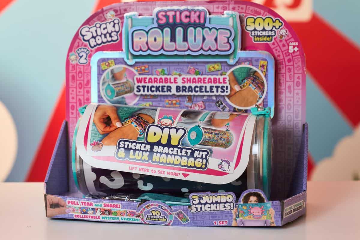 Colorful packaging of "Sticki Rolluxe" sticker bracelet kit, a Top Toys 2025 pick for kids, featuring DIY wearable sticker bracelets, a luxe handbag, over 500 stickers, three jumbo rolls, and images of children using the product.