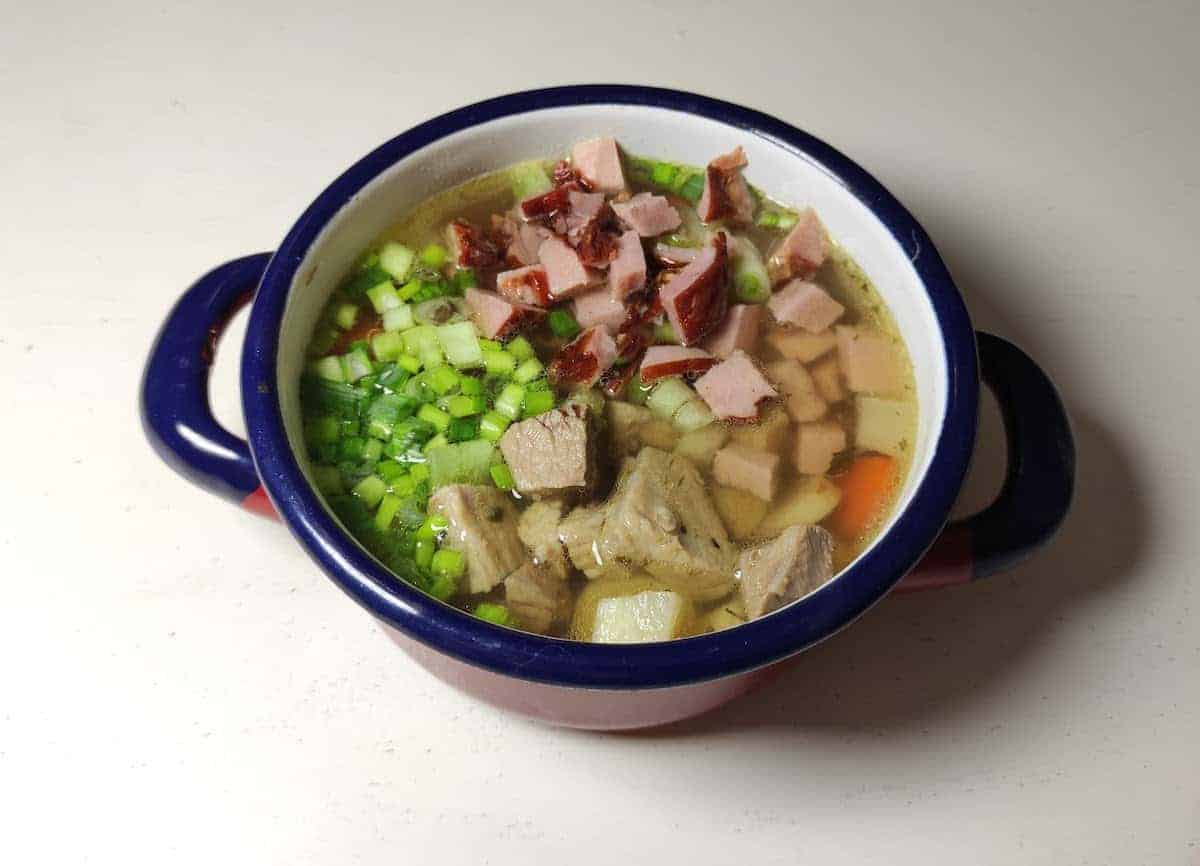 top view looking down on a bowl of ham soup topped with fresh chives 