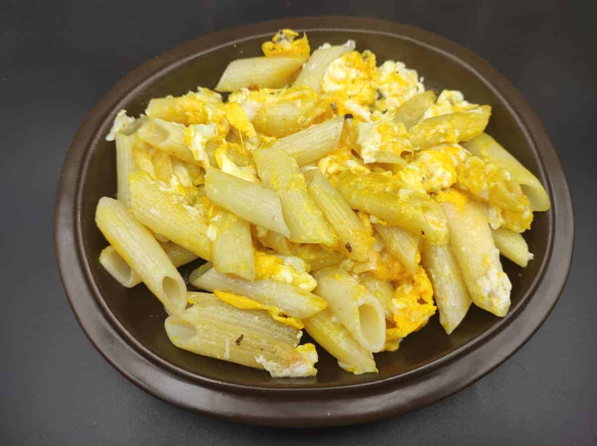 Pasta and egg in a brown plate.