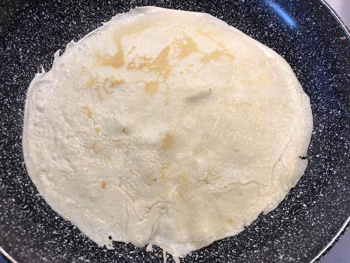 Golden brown nalesniki frying in a pan.