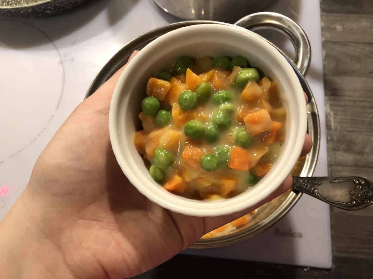 Carrots and green peas in a white bowl.