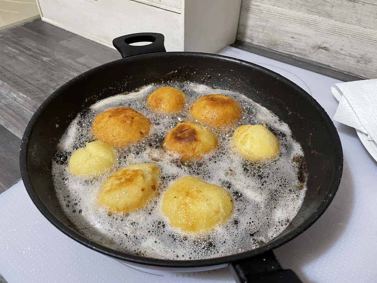 Krepliki donuts frying in oil.