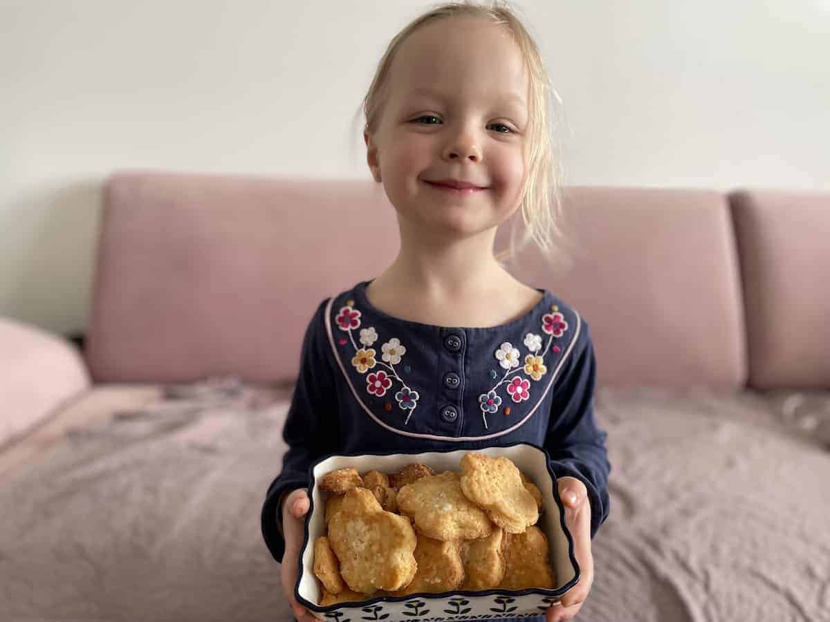 Child holding Polish ammonia cookies in a tray.