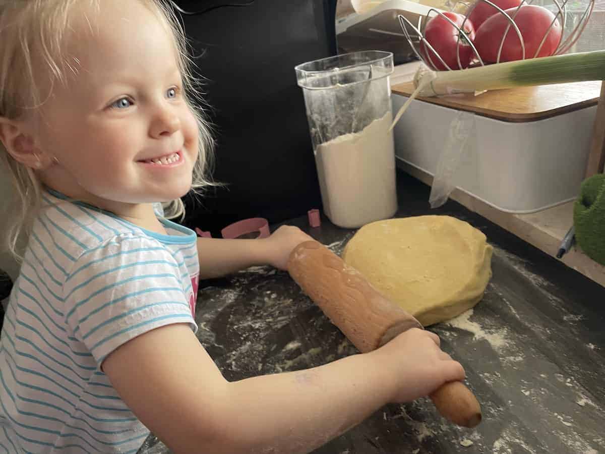 Child rolling out cookie dough.