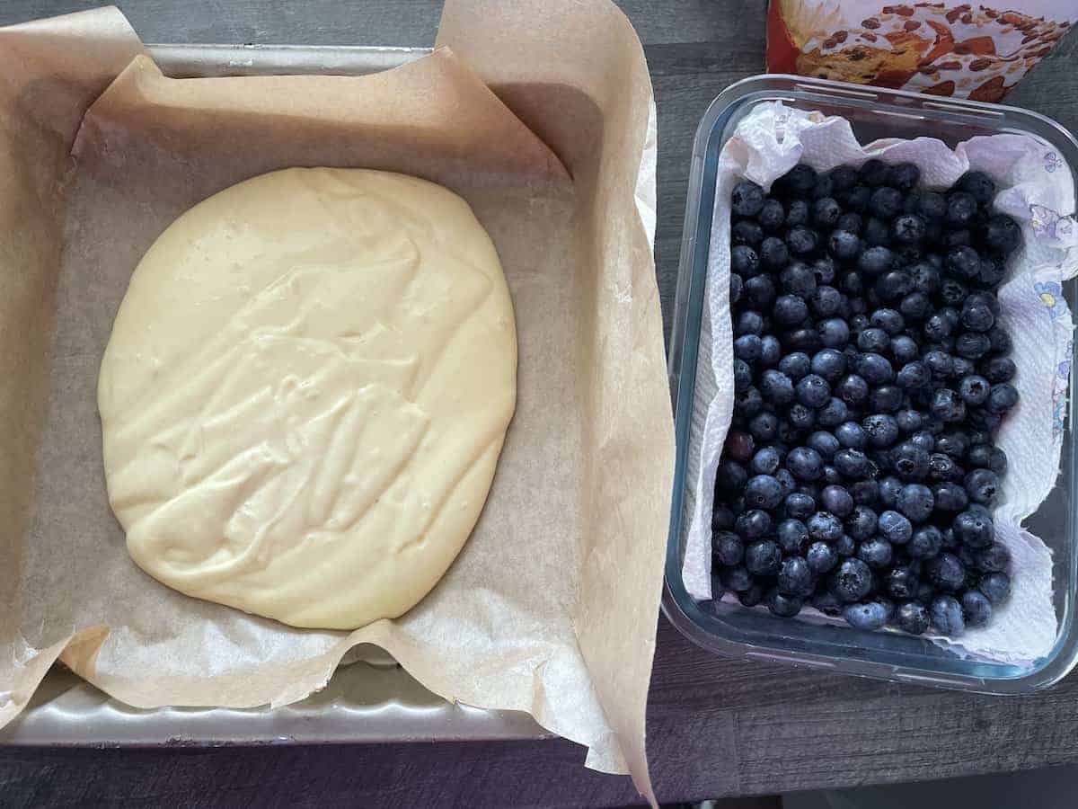 The dough of the polish blueberry cake is poured into the pan.