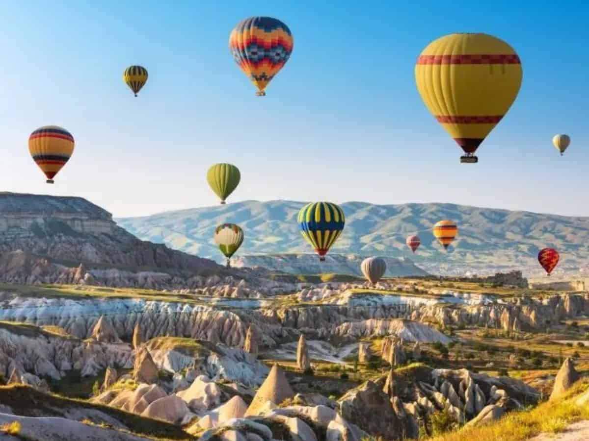 Fantastic Things to Do in Cappadocia. Fantastic Things to Do in Cappadocia. Colourful hot air ballooons flying over Cappadocia landscape, against a blue sky
