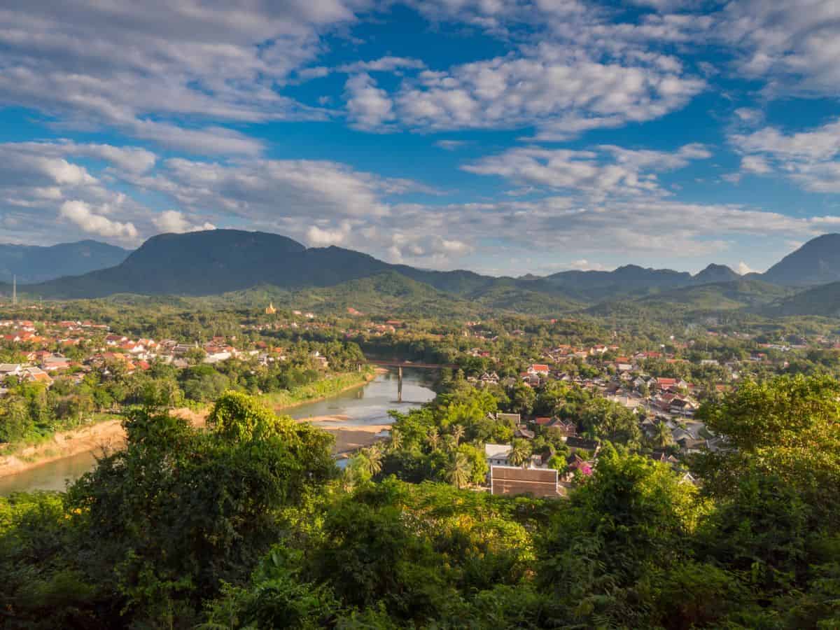 3-Day Luang Prabang Itinerary, Laos 3-Day Luang Prabang Itinerary, Laos - aerial view of the town with blue sky and white clouds above and green trees in foreground