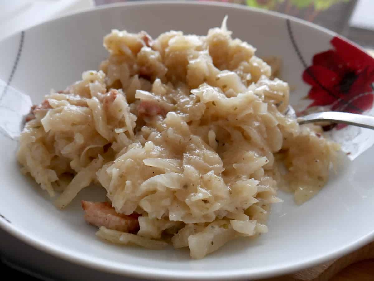 Fried cabbage and bacon in a white plate.