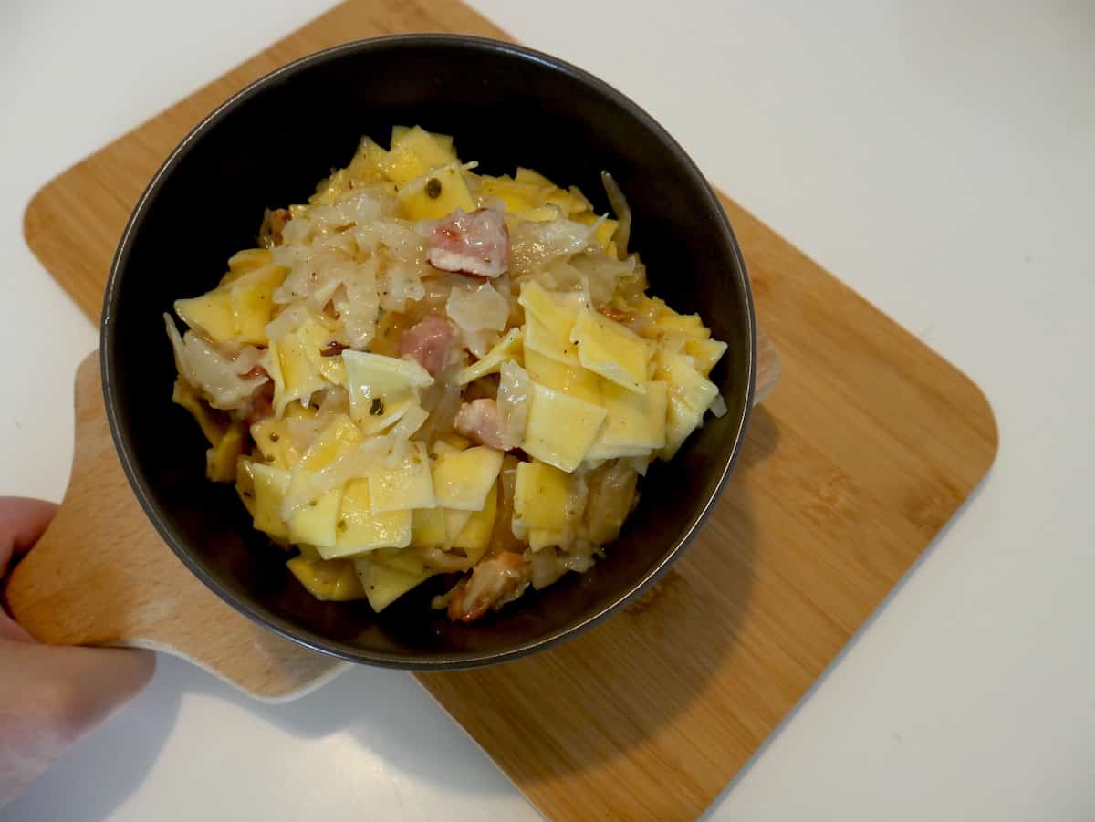 Lazanki in a black bowl on a brown board.