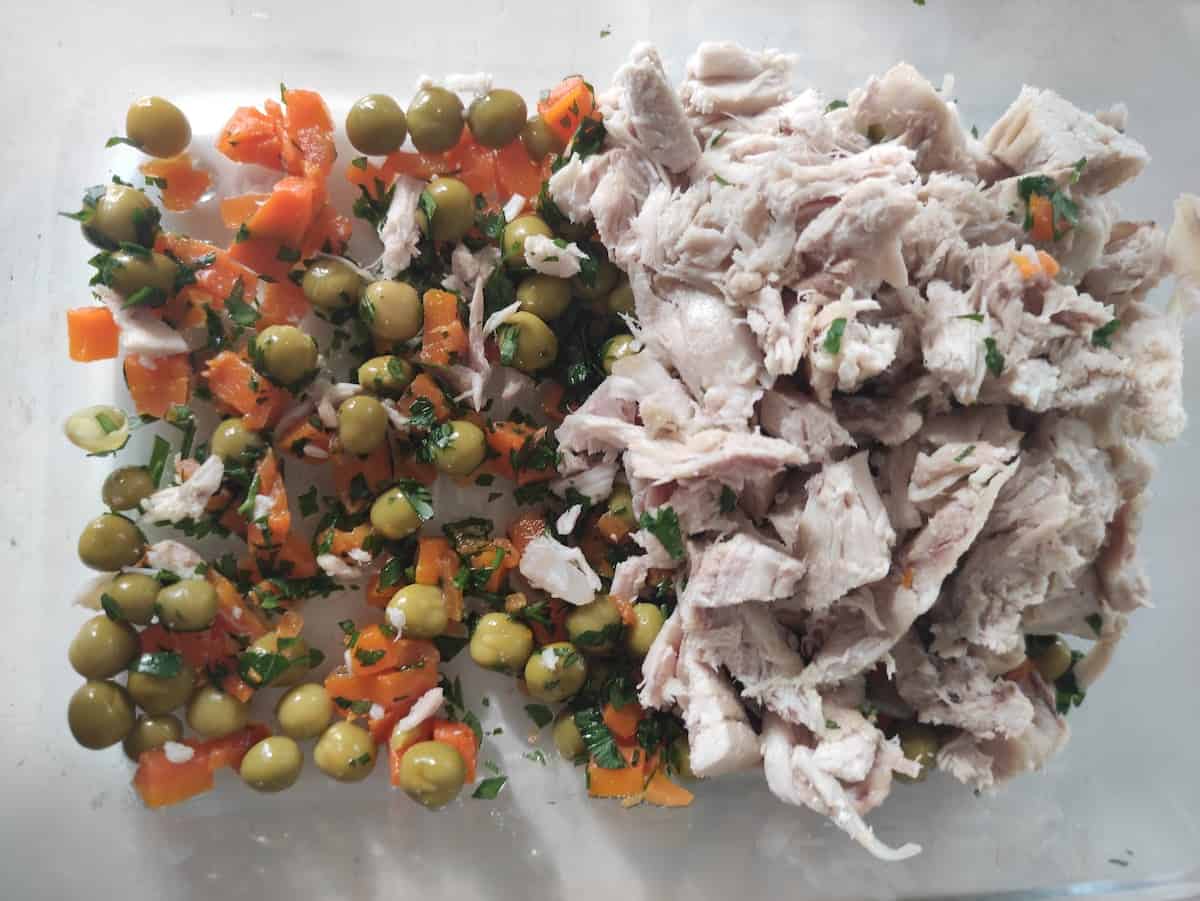 Carrots, peas and diced chicken on a white surface.