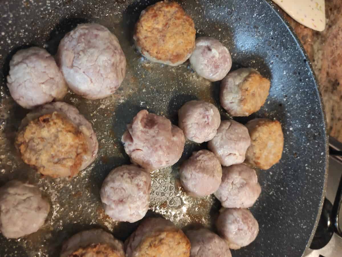 Meatballs frying in a pan.