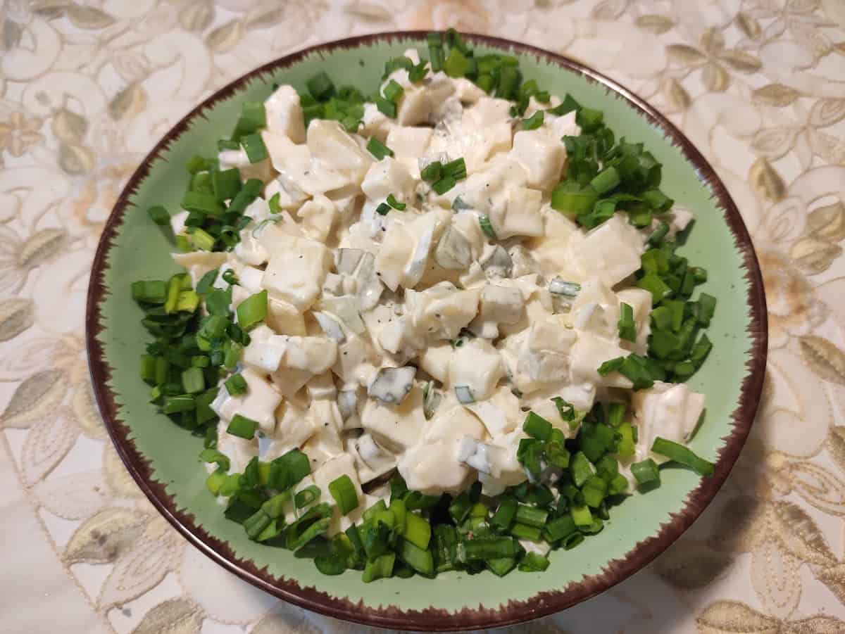 Polish potato salad sałatka ziemniaczana in a green bowl.