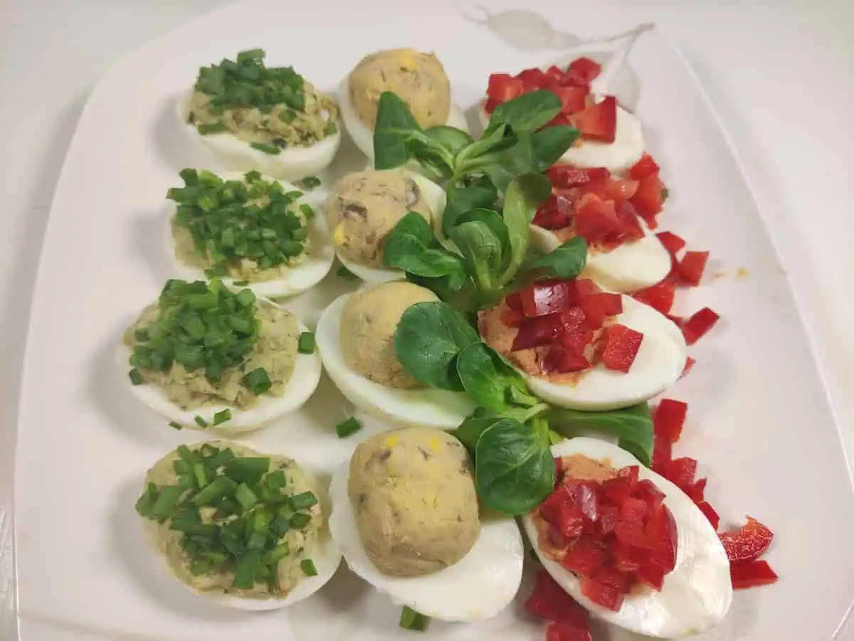 Polish deviled eggs with different toppings in a white plate.