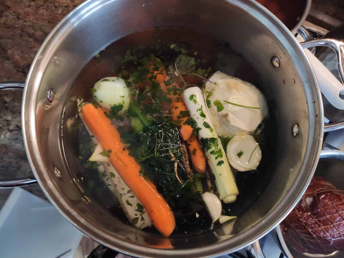 adding the veggies and ham to a pot on the stove 