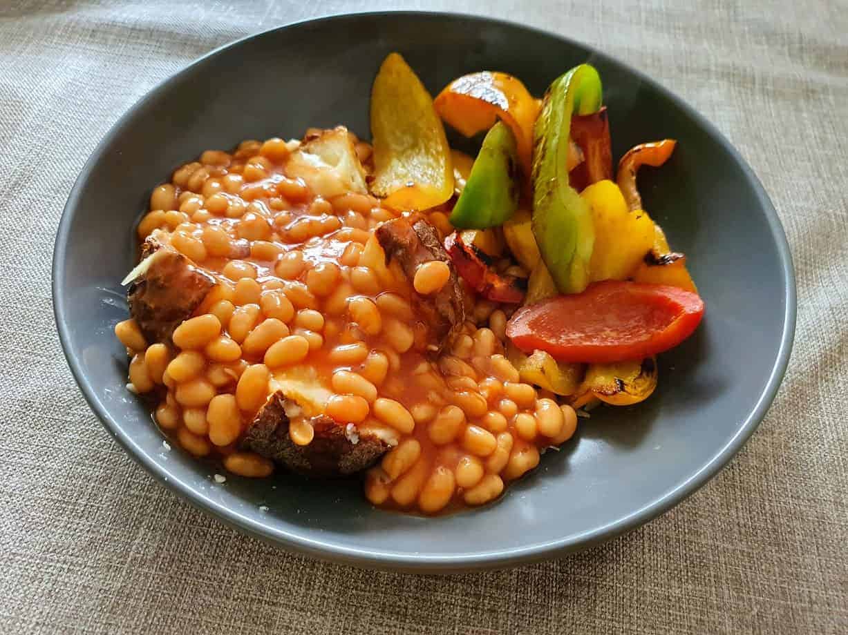 jacket potato topped with baked beans and served with roasted peppers