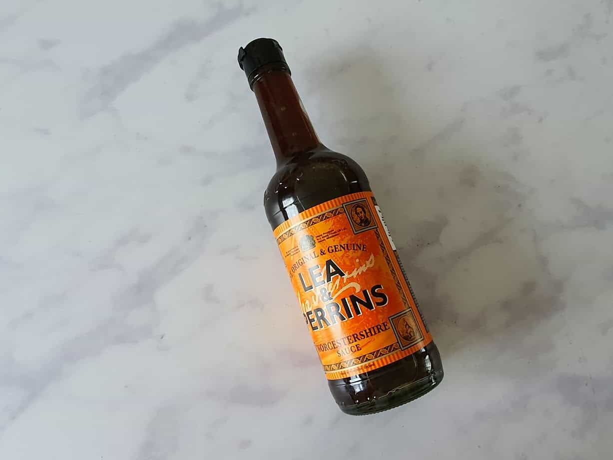 A bottle of Lea & Perrins Worcestershire sauce rests elegantly on a light surface, bringing a touch of B&M's unique selection to your kitchen essentials.